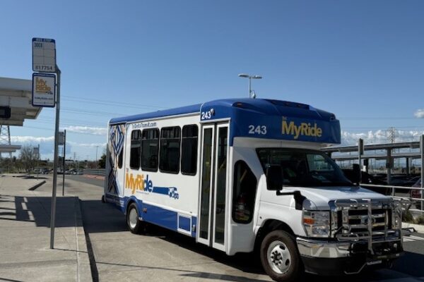 Tri MyRide microtransit vehicle pulling away from Antioch BART station